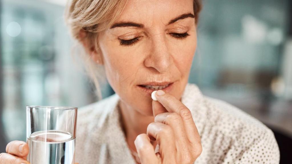 Imagen de una mujer tomándose un suplemento.