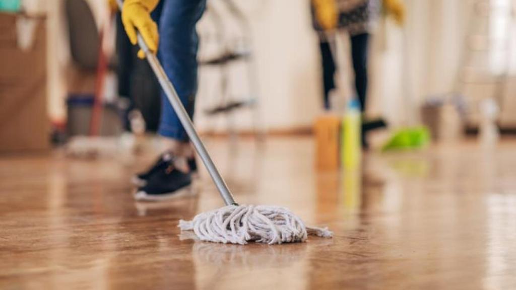 Una mujer limpiando el suelo con una fregona.