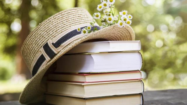 Un sombrero sobre una pila de libros acompañado de unas margaritas.