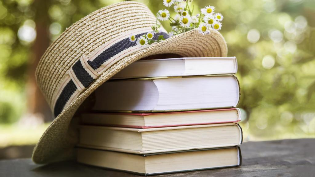 Un sombrero sobre una pila de libros acompañado de unas margaritas.