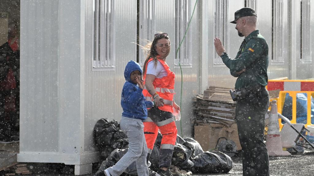 Un guardia civil saluda a menor llegado al puerto de La Restinga (El Hierro), tras el rescate de una patera con 45 ocupantes.