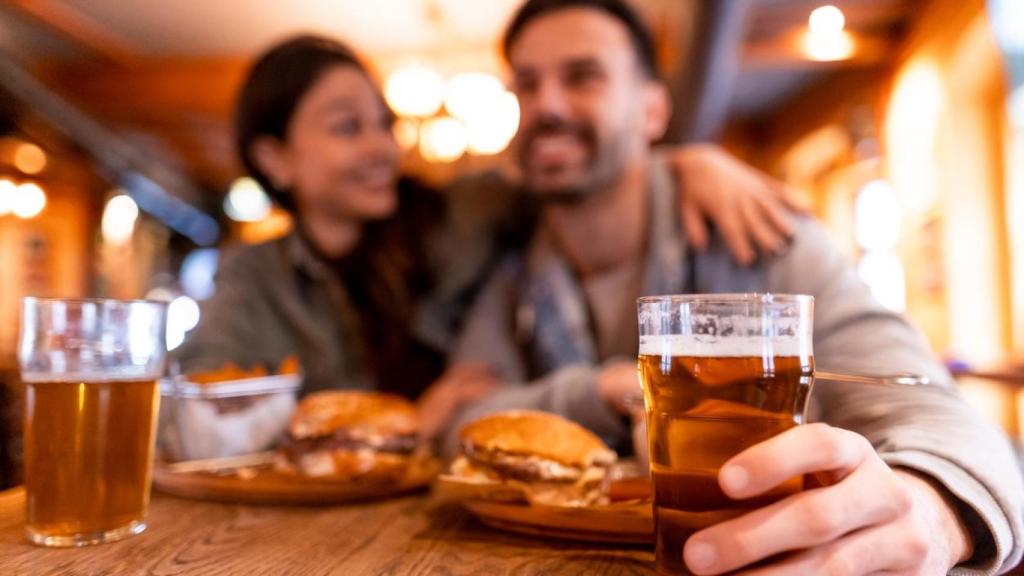 Pareja cenando con cervezas.