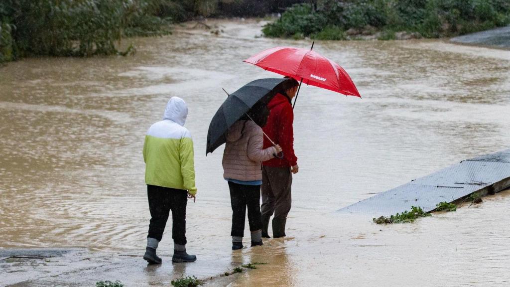 Varias personas tratan de cruzar una rambla durante el temporal de la primera semana de marzo en España.