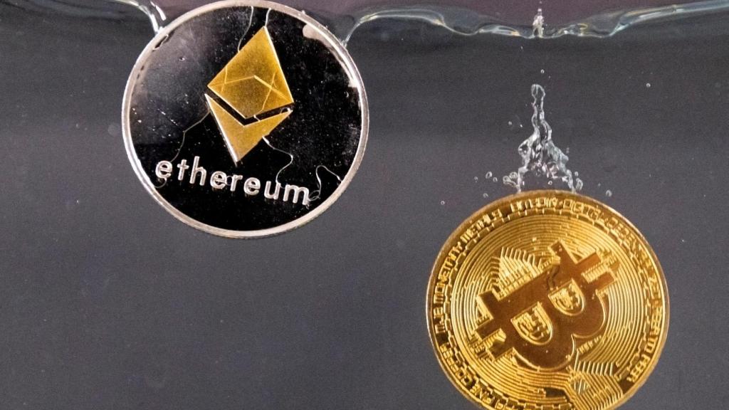 : Fichas de recuerdo que representan la criptomoneda bitcoin y la red Ethereum, con su token nativo ether, se sumergen en el agua en esta ilustración tomada el 17 de mayo de 2022.