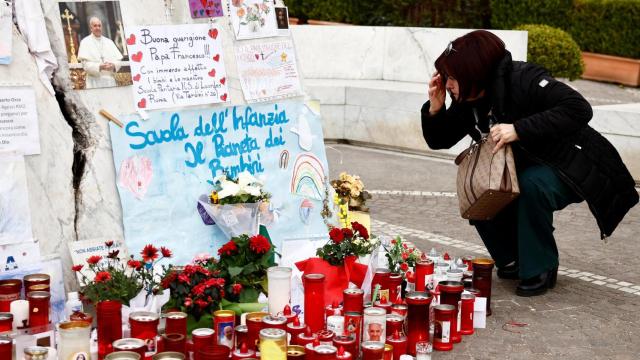Una mujer reza junto a la estatua del difunto Juan Pablo II en el exterior del Hospital Gemelli, donde el papa Francisco está ingresado desde el pasado 14 de febrero.