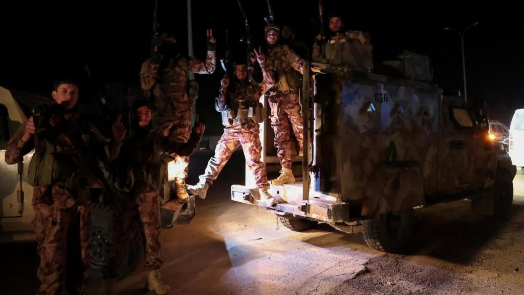 Las fuerzas sirias viajan en vehículos militares en su camino hacia Latakia, en Alepo.