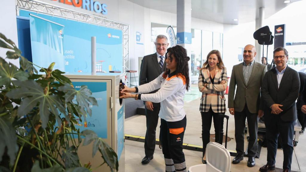 Una trabajadora de la estación de servicio metiendo la botella de aceite usado en el contenedor.