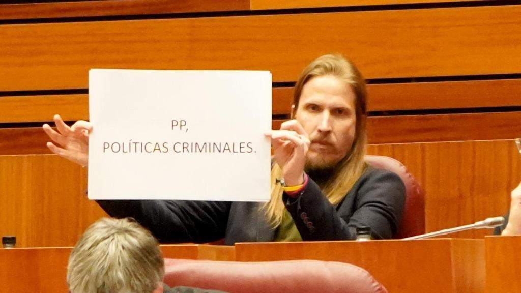Pablo Fernández sosteniendo un cartel con las palabras PP, políticas criminales