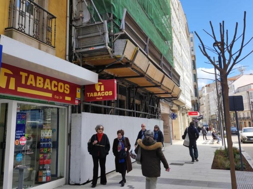 Viandantes delante de las ruinas del 140 de la calle San Andrés, con andamios y una red.