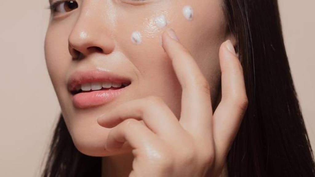 Mujer coreana aplicándose crema.
