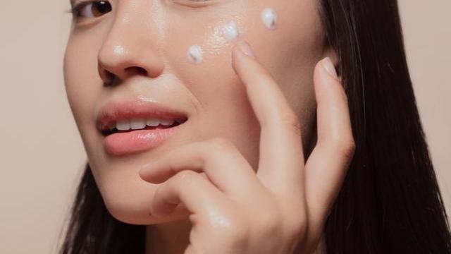 Mujer coreana aplicándose crema.