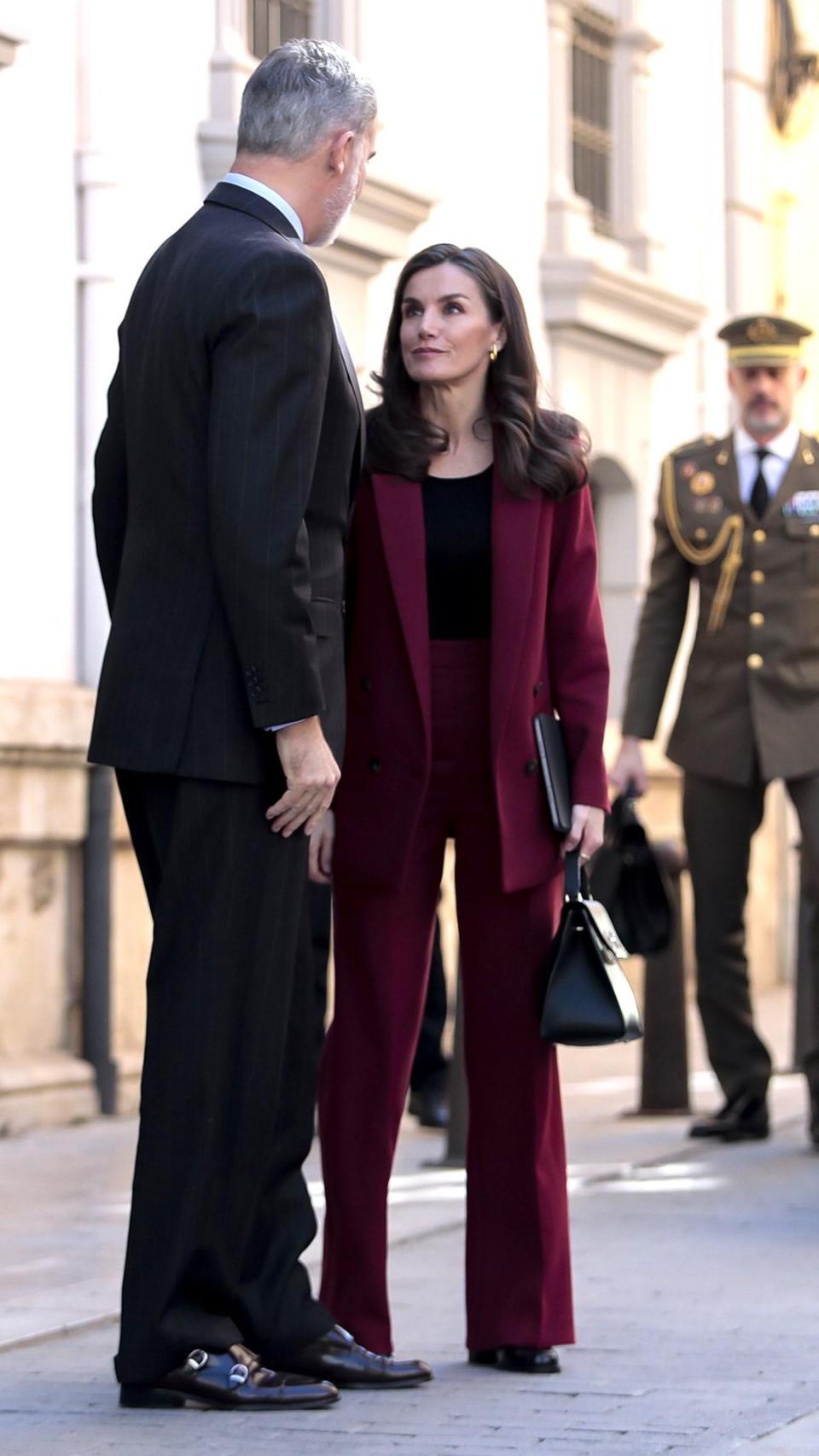 La Reina, con traje de Sezáne y pendientes de SIngularu, junto a Felipe VI.