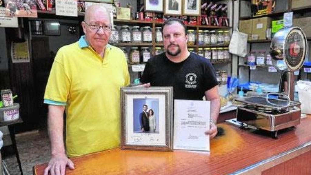 Eduardo Solano (d) y su padre, Juan (i), muestran una foto y una carta de agradecimiento de los Reyes de España a Tostadero Solano.