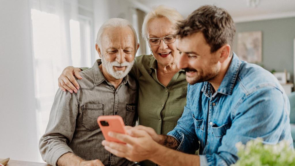 Un hijo enseña a sus padres el funcionamiento del teléfono móvil.