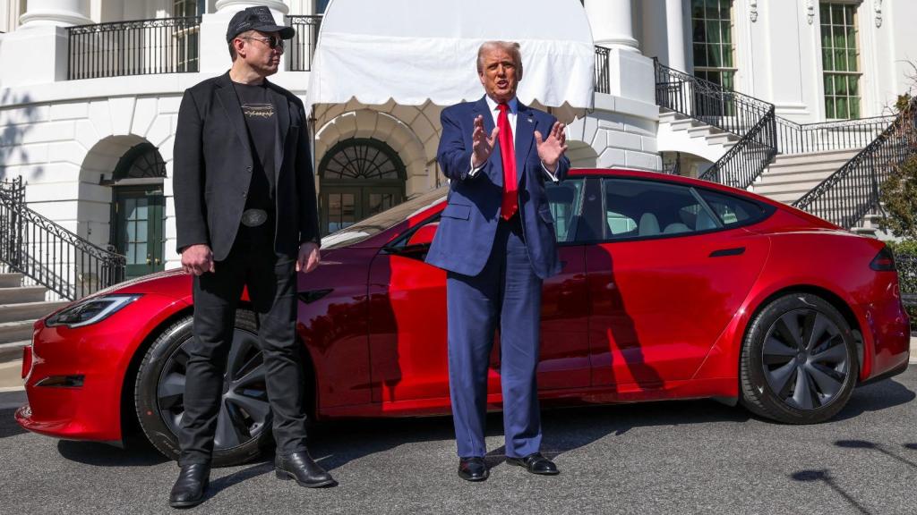 Elon Musk (i) y Donald Trump (d) frente a un vehículo Tesla.