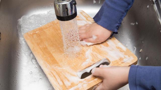 Una persona lavando una tabla de cortar