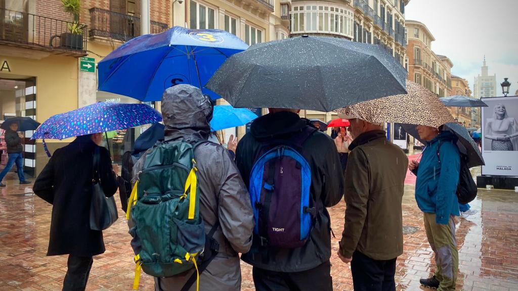 Un grupo de personas bajo la lluvia en la plaza de la Constitución de Málaga.