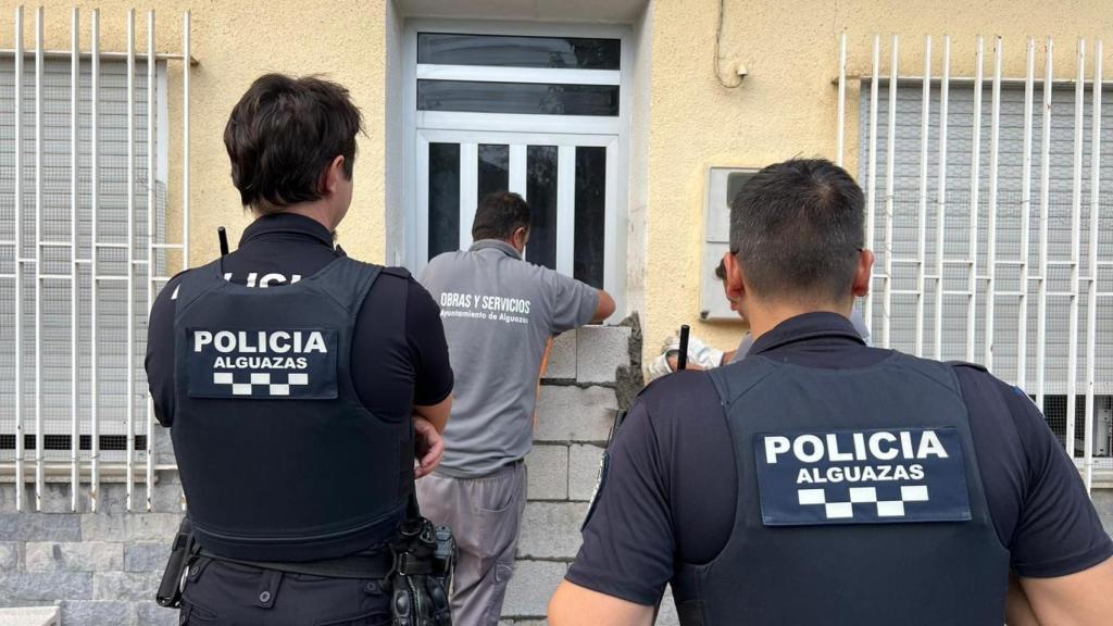 Un operario municipal, escoltado por dos policías locales de Alguazas, mientras levante un tabique en una casa okupa.
