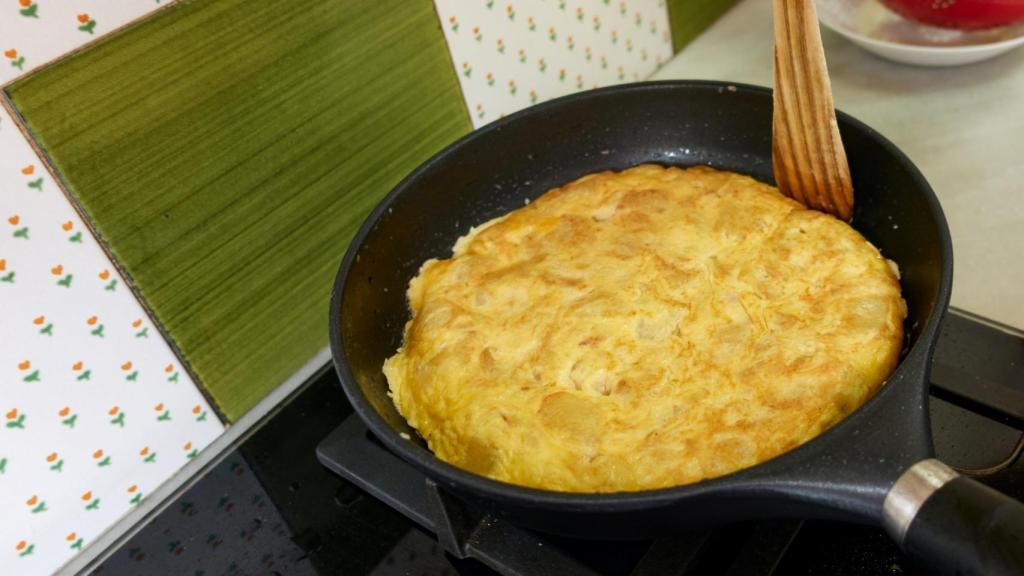 Una persona cuajando una tortilla de patata (Imagen de archivo)