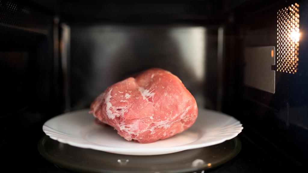 Un trozo de cerdo congelado en el microondas.