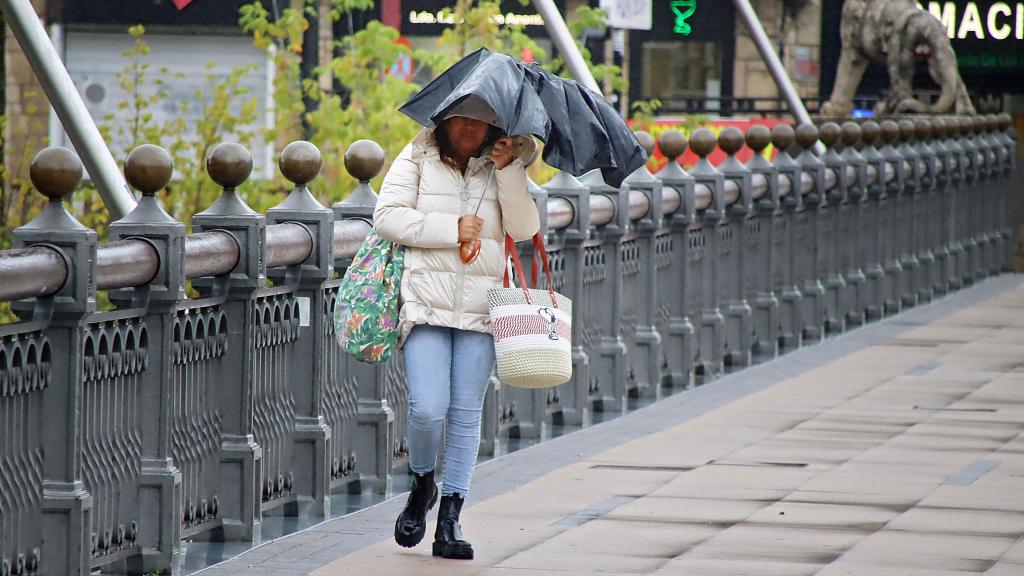 Imagen de archivo de una mujer caminando con un paraguas.