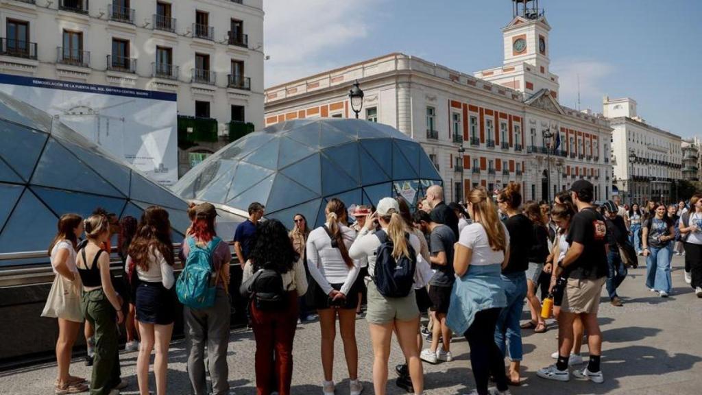 Varias personas atienden a la charla de un guía en la Puerta del Sol de Madrid.