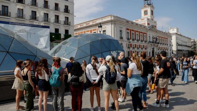 Varias personas atienden a la charla de un guía en la Puerta del Sol de Madrid.
