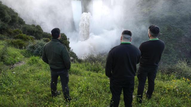 Varias personas observan el desembalse de la presa de Casasola, en Almogía, Málaga.