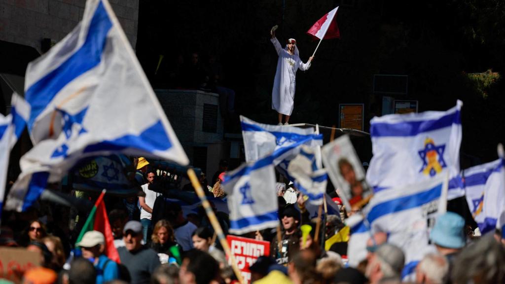 La gente ondea banderas en una manifestación contra el primer ministro israelí, Benjamin Netanyahu, y su gobierno, donde los manifestantes exigen la liberación de todos los rehenes de Gaza , cerca de la residencia de Netanyahu en Jerusalén.