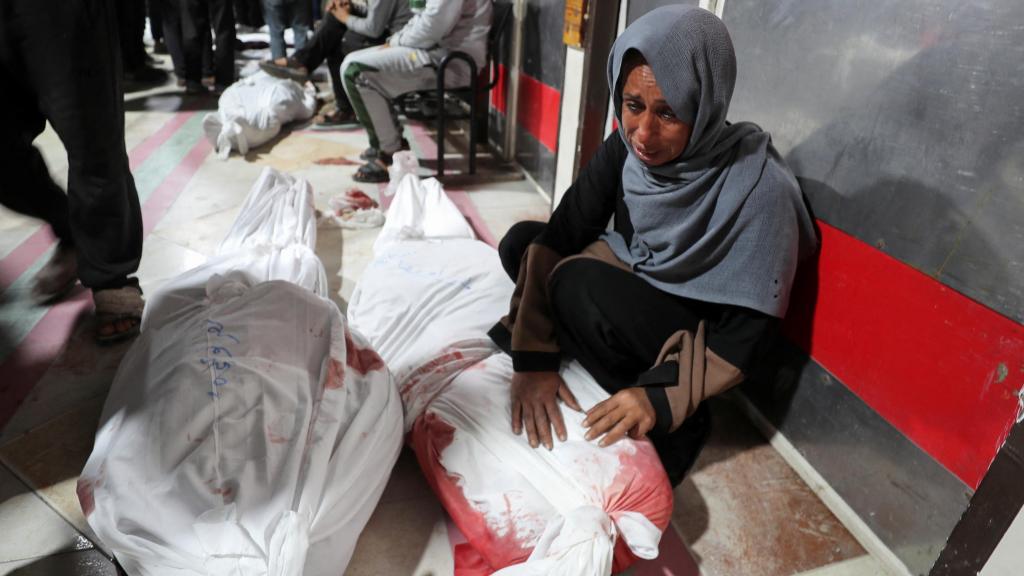 Una mujer llora delante de los cadáveres de varios seres queridos en un hospital de Gaza.