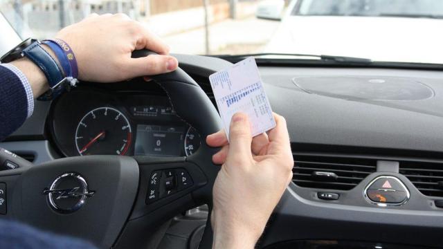 Un conductor con su carnet de conducir en la mano.