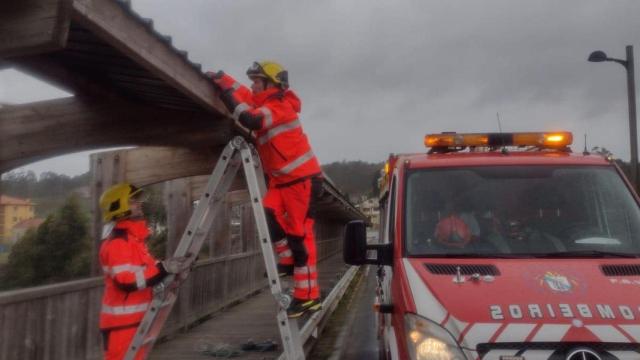 Los bomberos aseguran unas chapas en un puente en Rianxo.