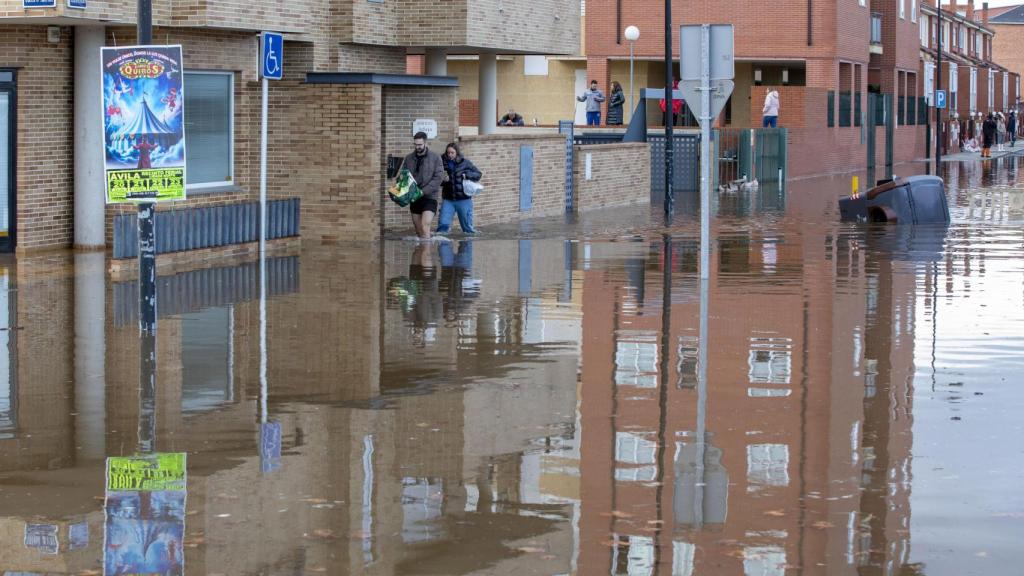 Varios vecinos caminan por una calle completamente inundada