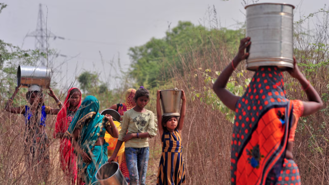 Mujeres y niñas cargando con cubos de agua hasta sus hogares.