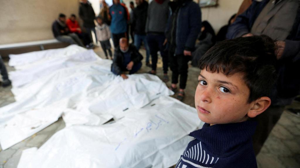 Un niño gazatí delante de varias víctimas de los bombardeos israelíes.
