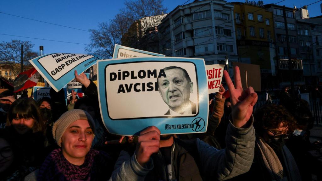 Una persona sostiene un cartel con la imagen del presidente turco Tayyip Erdogan que dice Cazador de diplomas, mientras estudiantes participan en una protesta contra la detención del alcalde de Estambul, Ekrem Imamoglu, en Estambul, Turquía, el 21 de marzo de 2025.