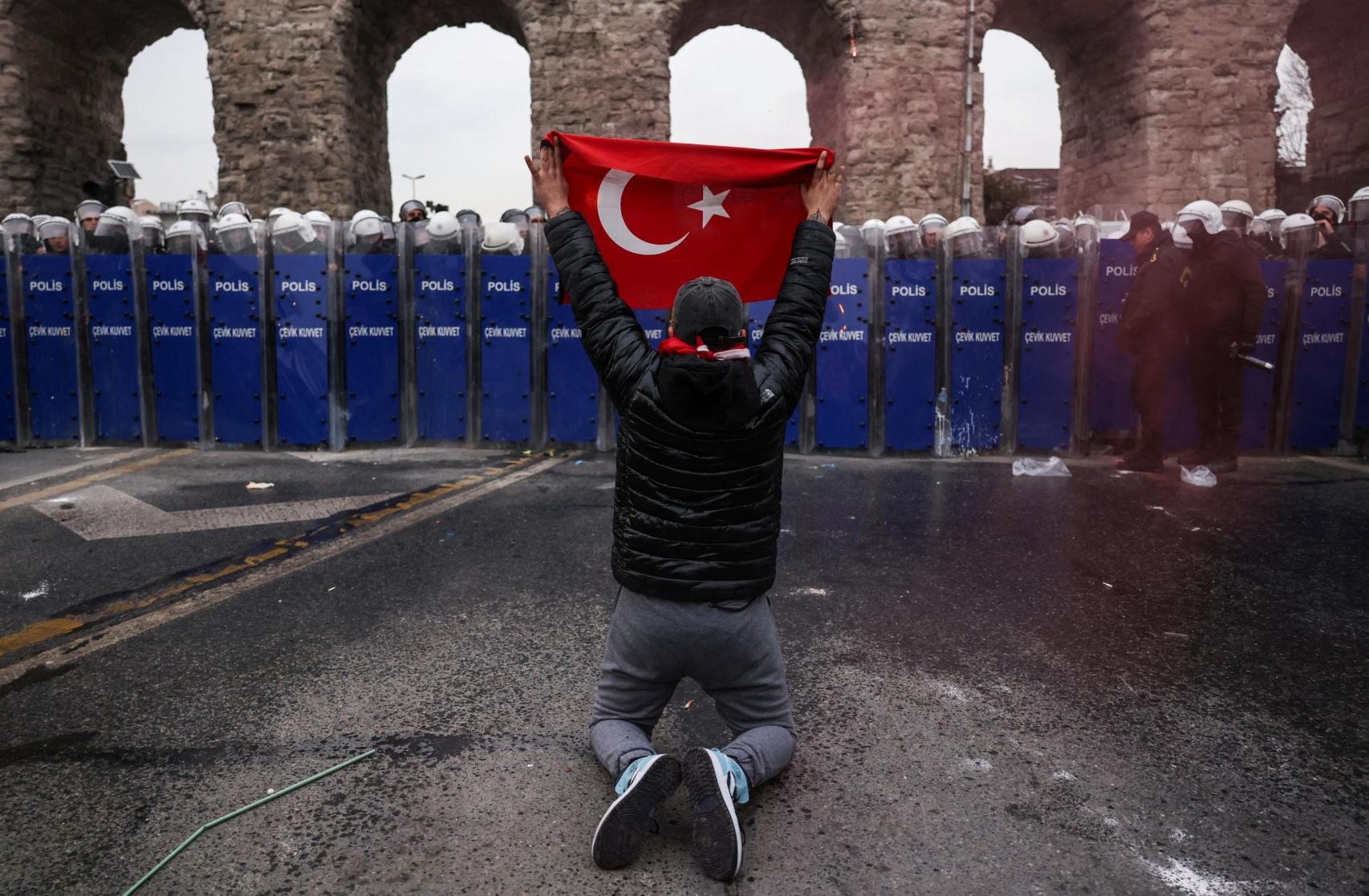 Un manifestante extiende una bandera turca frente a la Policía.