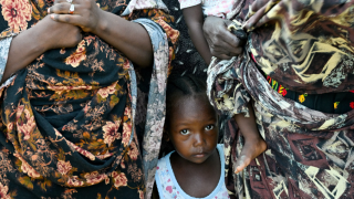 Un niño se encuentra entre dos mujeres en una escuela convertida en refugio, en Puerto Sudán, Sudán.