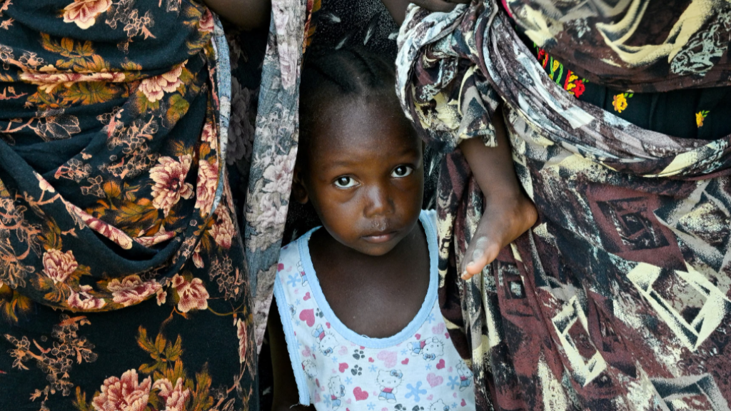 Un niño se encuentra entre dos mujeres en una escuela convertida en refugio, en Puerto Sudán, Sudán.