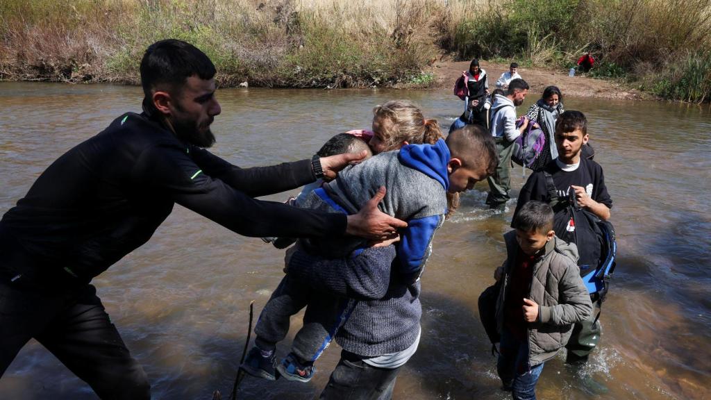Un hombre ayuda a un hombre sirio con niños, que huyó de la violencia en el oeste de Siria, en el río Nahr El Kabir, después de los asesinatos masivos reportados de miembros de la minoría alauita , en Akkar, Líbano, el 11 de marzo de 2025.