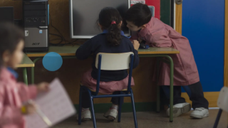 Dos niños en un colegio usando un ordenador.