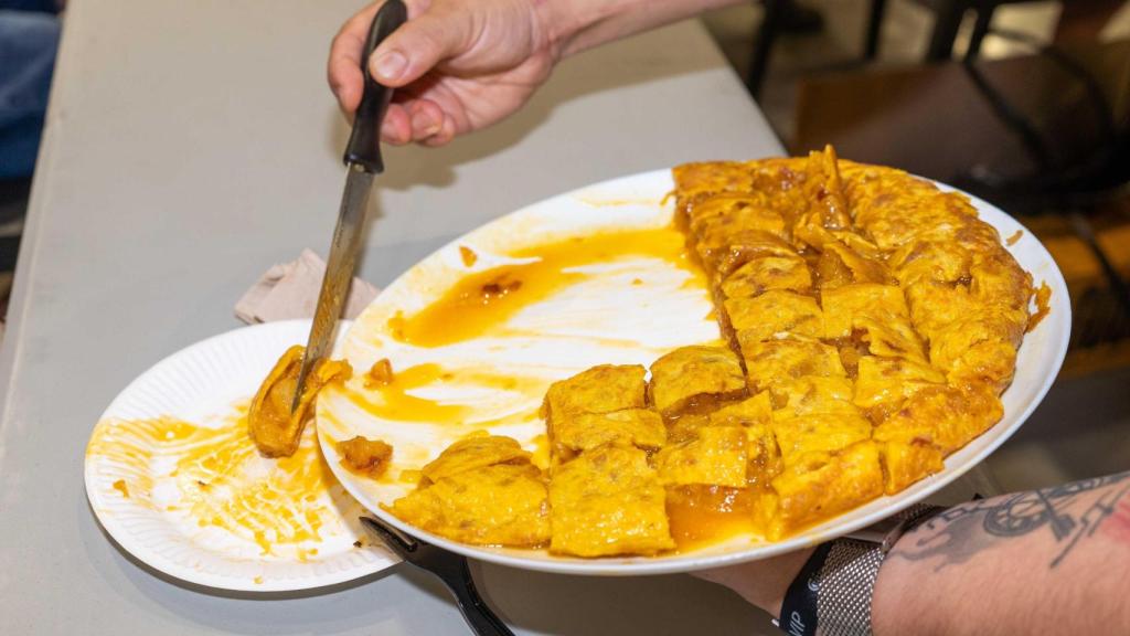 Un hombre sirve tortilla de patatas.