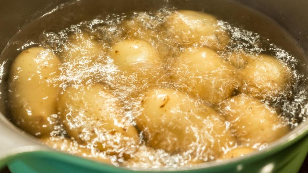 Patatas cocinándose en una cacerola con agua en ebullición.