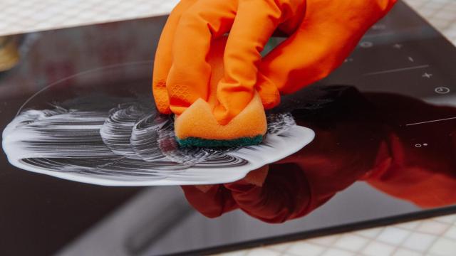 Una persona limpia la vitrocerámica con un producto en pasta