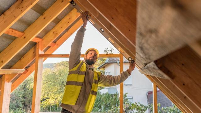 Un carpintero trabajando en la construcción de un tejado con madera
