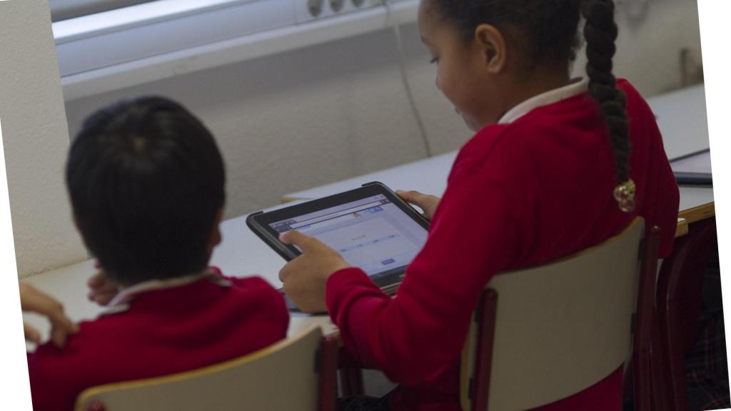Dos niños en un colegio estudiando con una tablet.