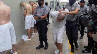 Fotografía que muestra a guardias en el Centro de Confinamiento del Terrorismo (Cecot) transfiriendo a supuestos miembros del Tren de Aragua, en San Luis Talpa, El Salvador.