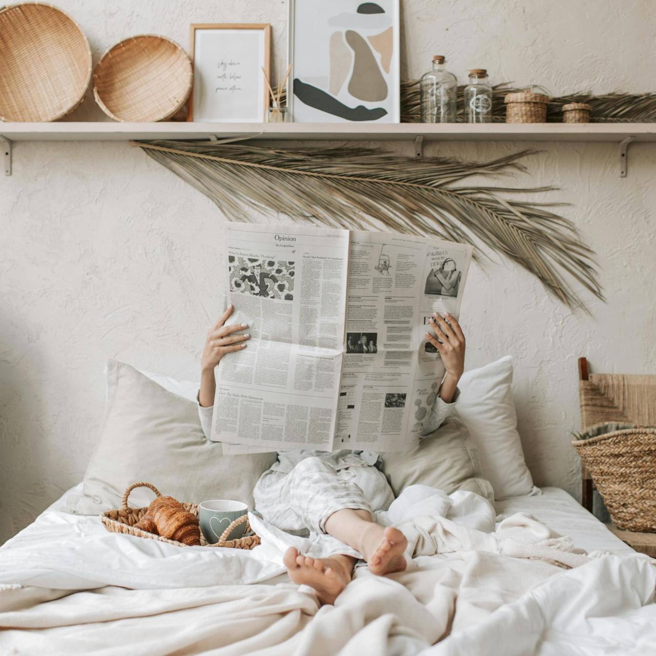 Mujer leyendo el periódico en su dormitorio y completamente desconectada del mundo digital.