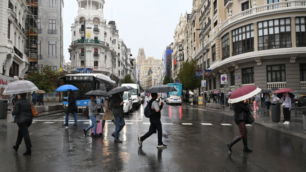 Personas se protegen de la lluvia en la Gran Vía de Madrid.