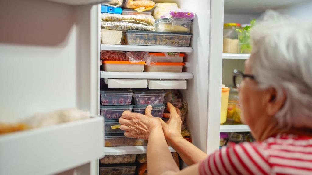 Una persona ordenando el congelador (Imagen de archivo)